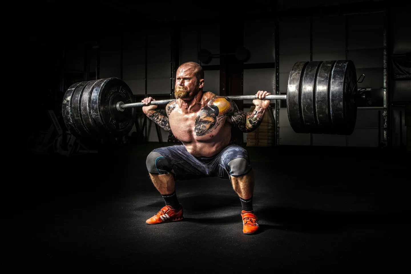 A lifter under a heavily loaded barbell at the bottom of a squat
