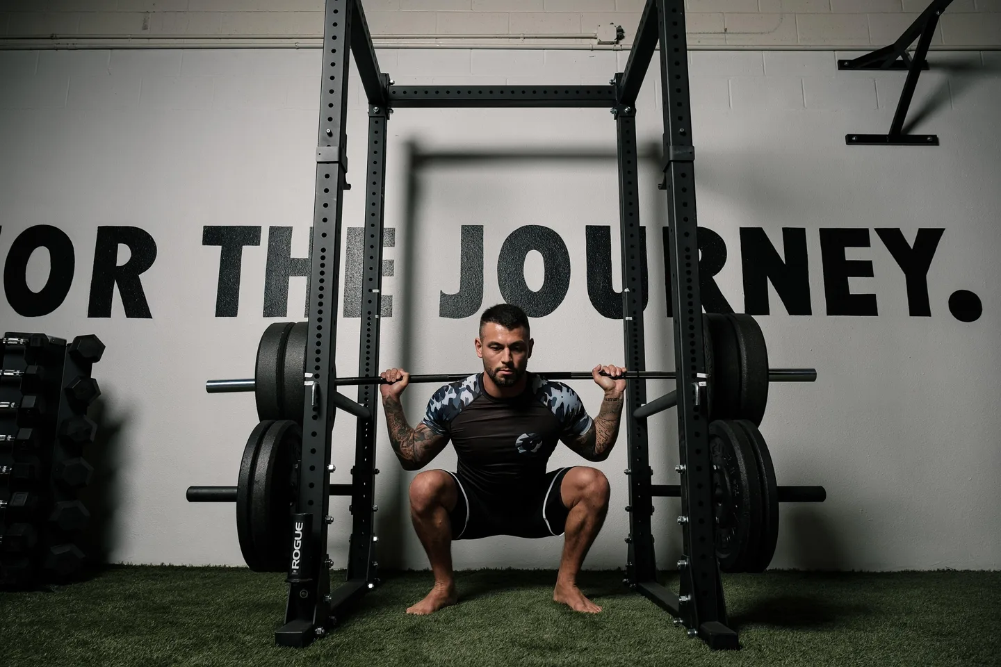 A lifter holds a barbell back squat at the bottom position inside a power rack