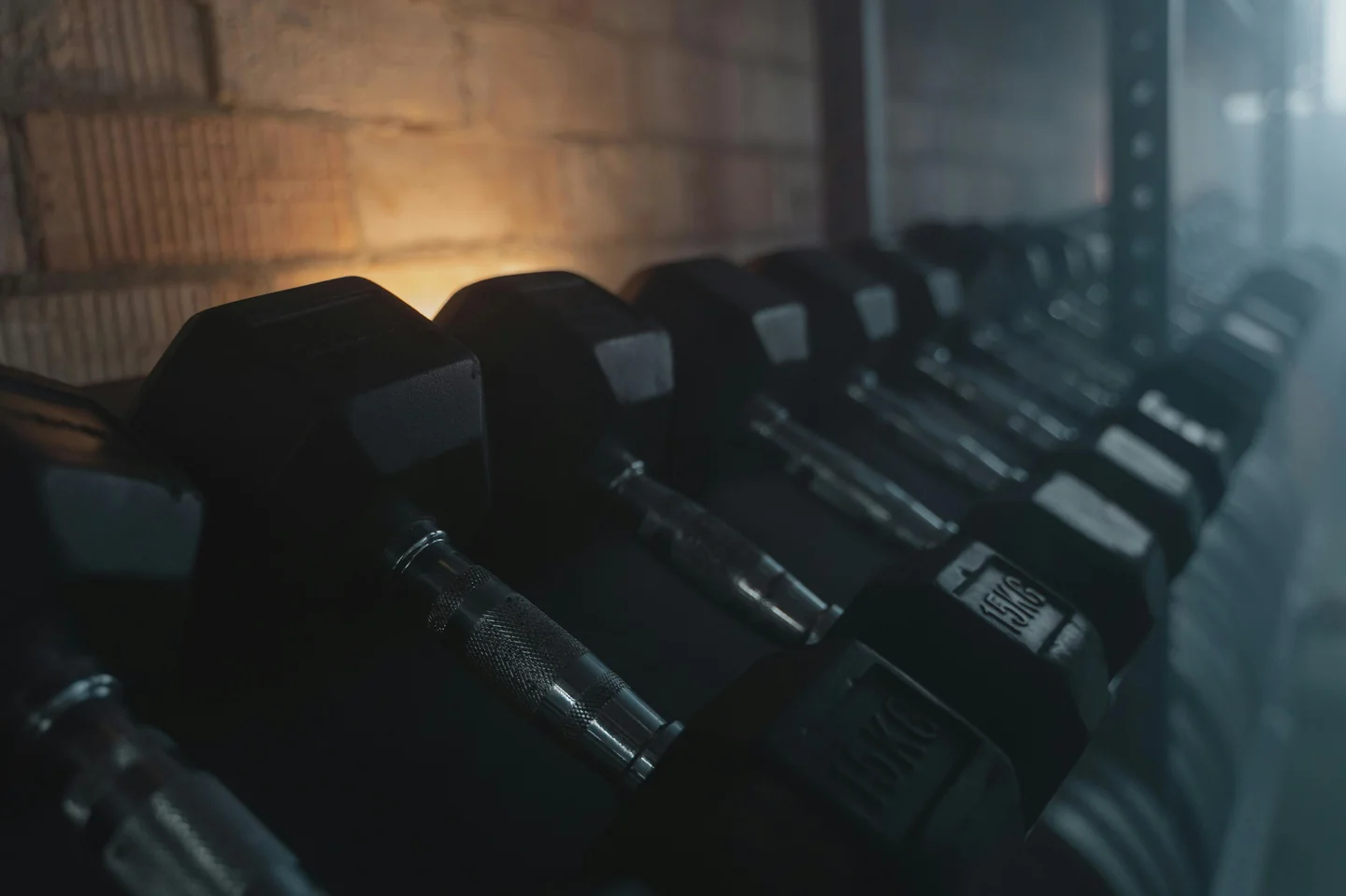 A rack of hex dumbbells in a dimly lit home gym