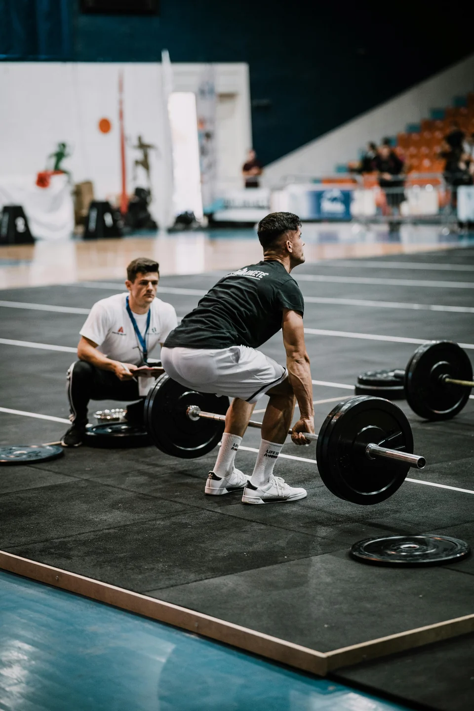 A competitive deadlifter setting up at a loaded bar on a competition platform