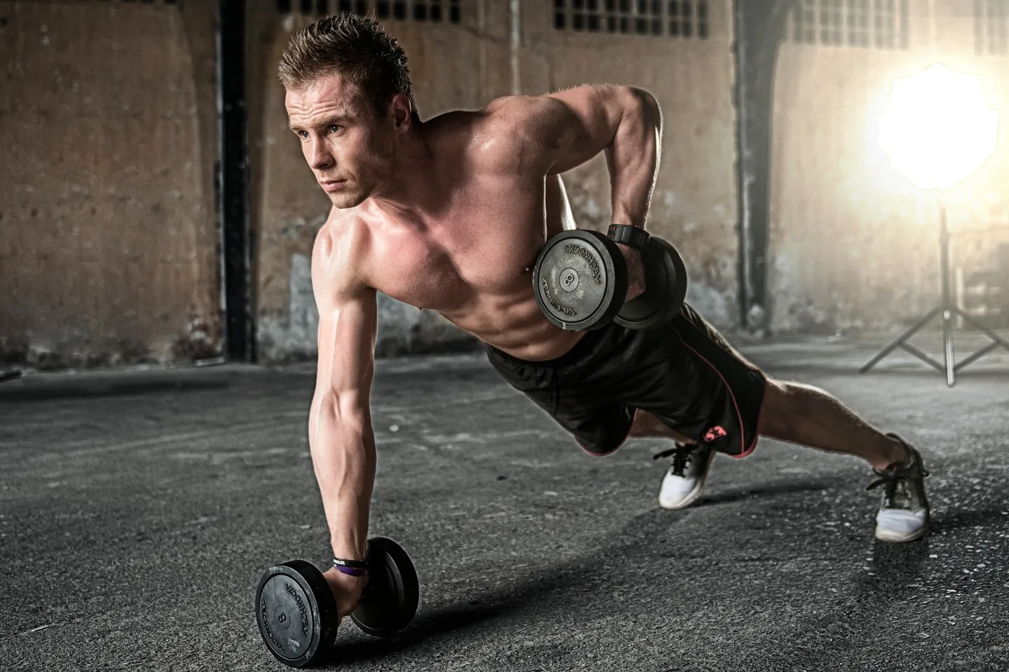 A lifter mid-set with dumbbells in a gym